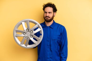 Genç adam üzgün, üzgün ya da kızgın hissediyor ve yana bakıyor. araba mekaniği kavramı