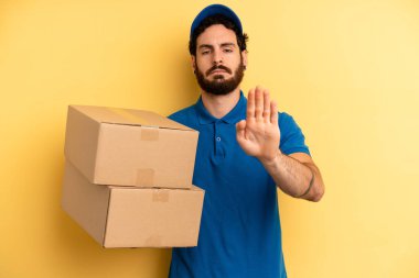 Genç adam ciddi görünüyor. Avuç içi gösteriyor. Durma hareketi yapıyor. Şirket çalışanı konsepti