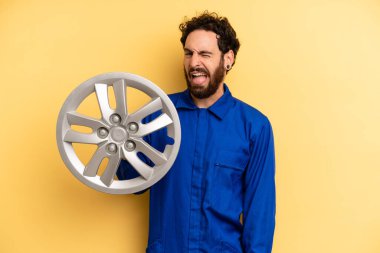 Neşeli ve asi tavırlı genç bir adam, şaka yapıyor ve dilini dışarı çıkarıyor. araba mekaniği kavramı