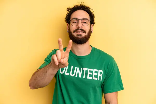 Joven Sonriendo Buscando Amigable Mostrando Número Dos Concepto Voluntario —  Fotos de Stock