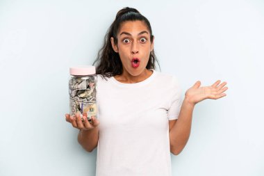 İspanyol kadın şaşırmış ve şok olmuş görünüyor. Çenesi düşmüş ve elinde bir nesne tutuyor. kaydetme kavramı