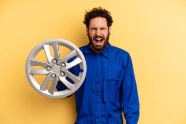 Genç adam agresif bir şekilde bağırıyor, çok kızgın görünüyor. araba mekaniği kavramı