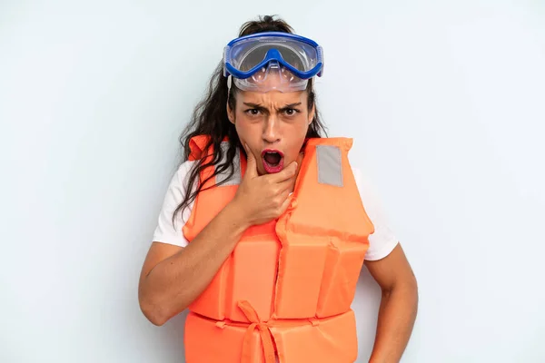 hispanic woman with mouth and eyes wide open and hand on chin. life jacket and summer concept