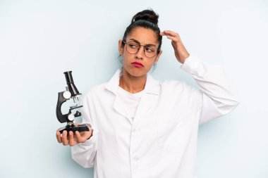 hispanic woman feeling puzzled and confused, scratching head. scients student