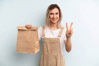 Sarışın kadın gülümsüyor ve arkadaş canlısı görünüyor. İki numarayı gösteriyor. teslimat kavramını kaldır