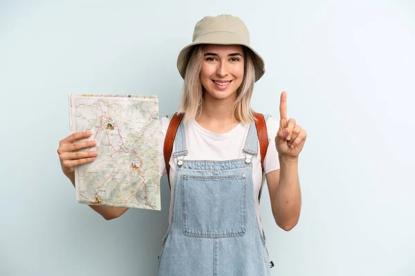 Blonde Woman Smiling Looking Friendly Showing Number One Tourist Map — Zdjęcie stockowe