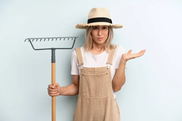 Blonde Woman Feeling Puzzled Confused Doubting Farmer Rake Cocnept — Foto Stock