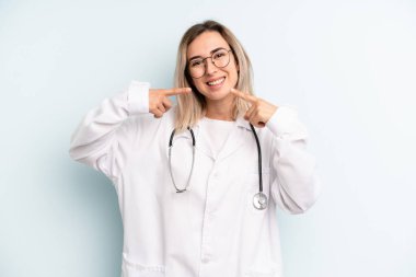 Kendine güvenen sarışın kadın kendi gülüşünü işaret ediyor. tıp öğrencisi konsepti