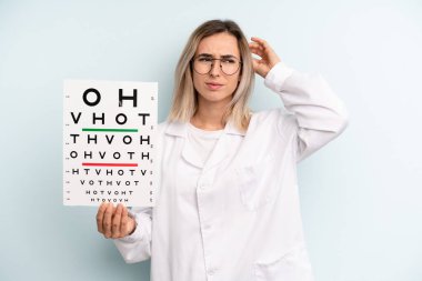 Kafası karışmış, kafası karışmış, kaşınan sarışın bir kadın. optik görüş testi konsepti