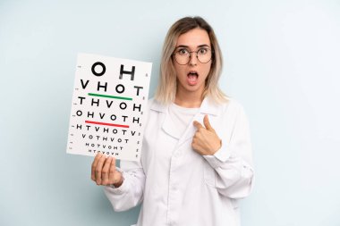 Şok olmuş ve ağzı açık, kendini gösteren sarışın bir kadın. optik görüş testi konsepti