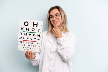 Gülümseyen, mutlu, kendine güvenen, elleri çenesinde bir sarışın kadın. optik görüş testi konsepti