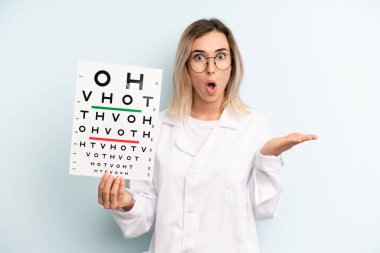 Sarışın kadın şaşırmış ve şok olmuş görünüyor. Çenesi düşmüş ve elinde bir nesne var. optik görüş testi konsepti