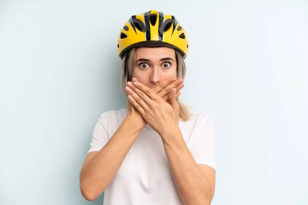 blonde woman covering mouth with hands with a shocked. bike sport concept