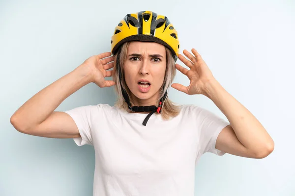 blonde woman feeling stressed, anxious or scared, with hands on head. bike sport concept