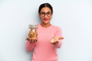 İspanyol kadın mutlu bir şekilde gülümsüyor ve bir konsept sunuyor. Ev yapımı kurabiye konsepti