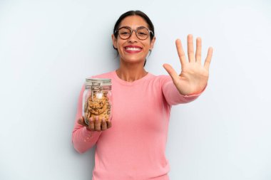 İspanyol kadın gülümsüyor ve arkadaş canlısı görünüyor, beş numarayı gösteriyor. Ev yapımı kurabiye konsepti