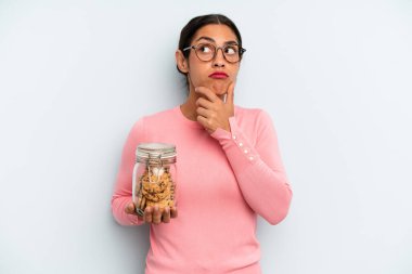 Hispanik kadın düşünüyor, kuşkulu ve şaşkın hissediyor. Ev yapımı kurabiye konsepti