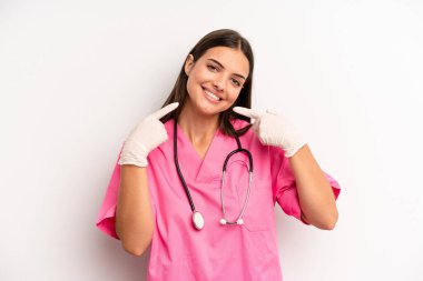 Kendine güvenen güzel bir kadın kendi gülüşünü işaret ediyor. hemşire konsepti