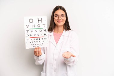 Güzel bir kadın mutlu bir şekilde gülümsüyor ve bir konsept sunuyor. optik görüş testi konsepti