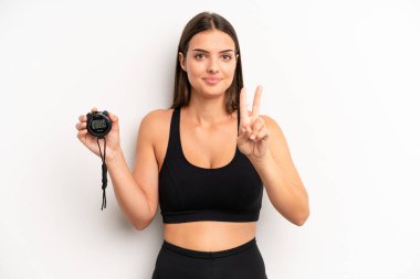 Güzel bayan gülümsüyor ve arkadaş canlısı görünüyor, ikinciyi gösteriyor. fitness konsepti