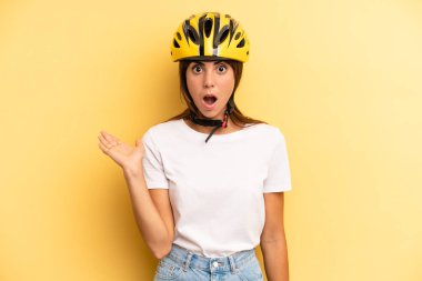 pretty woman looking surprised and shocked, with jaw dropped holding an object. bike sport concept