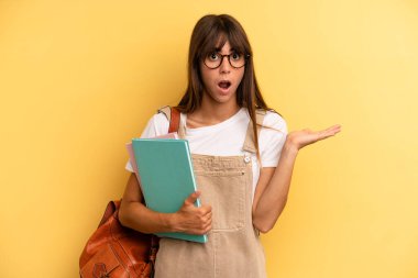 Güzel kadın şaşırmış ve şok olmuş görünüyor. Çenesi düşmüş ve elinde bir nesne tutuyor. Üniversite öğrencisi konsepti