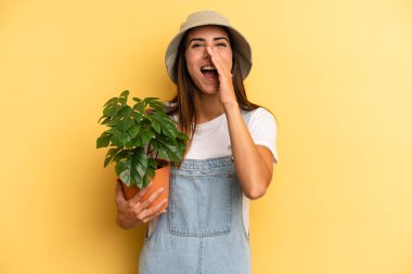 hispanic woman feeling happy,giving a big shout out with hands next to mouth. gardering concept
