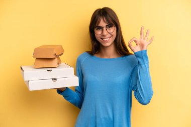 pretty woman feeling happy, showing approval with okay gesture. take away fast food concept