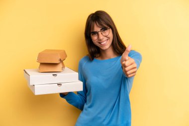 pretty woman feeling proud,smiling positively with thumbs up. take away fast food concept