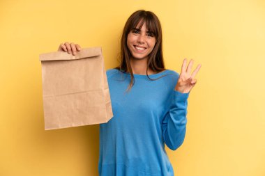 pretty woman smiling and looking friendly, showing number three. take away fast food concept
