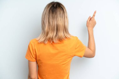 young adult pretty woman standing and pointing to object on copy space, rear view