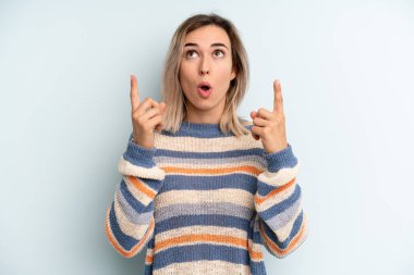 Şok olmuş, şaşkın ve ağzı açık, iki eliyle uzayı gösteren genç ve güzel bir kadın.