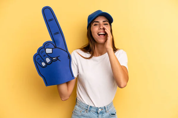 hispanic woman feeling happy,giving a big shout out with hands next to mouth. number one fan concept