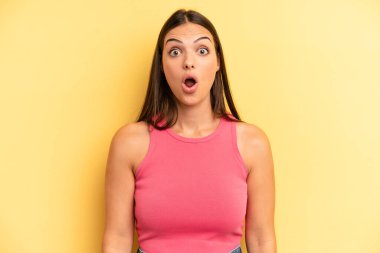 young adult pretty woman looking very shocked or surprised, staring with open mouth saying wow