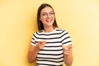 young adult pretty woman feeling happy, cool, satisfied, relaxed and successful, pointing at camera, choosing you