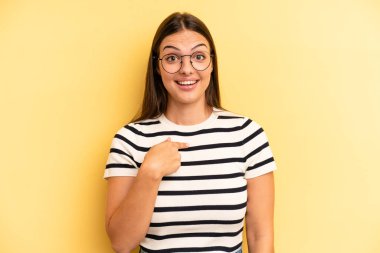 young adult pretty woman looking happy, proud and surprised, cheerfully pointing to self, feeling confident and lofty