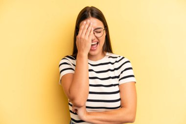 young adult pretty woman laughing and slapping forehead like saying doh! I forgot or that was a stupid mistake 