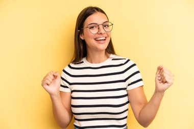 young adult pretty woman feeling happy, surprised and proud, shouting and celebrating success with a big smile