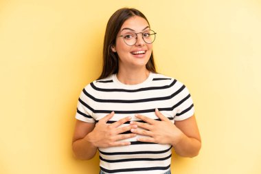 young adult pretty woman looking happy, surprised, proud and excited, pointing to self