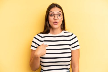 young adult pretty woman looking shocked and surprised with mouth wide open, pointing to self
