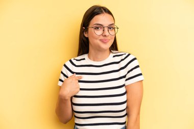 young adult pretty woman looking proud, confident and happy, smiling and pointing to self or making number one sign