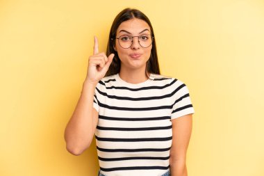young adult pretty woman feeling like a genius holding finger proudly up in the air after realizing a great idea, saying eureka