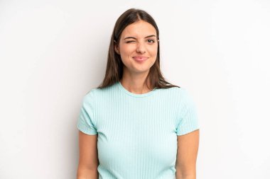 young adult pretty woman looking happy and friendly, smiling and winking an eye at you with a positive attitude