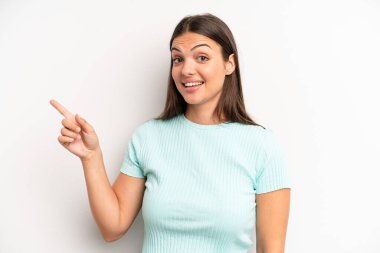 Genç ve güzel bir kadın heyecanlı ve şaşırmış görünüyor. Yana ve yukarıya bakıp boşluğu kopyalıyor.