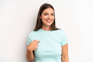 Genç ve güzel bir kadın gururlu, kendinden emin ve mutlu görünüyor, gülümsüyor ve kendini işaret ediyor veya bir numaralı işareti yapıyor.