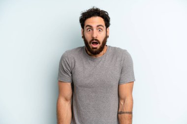 Genç, sakallı bir adam şok olmuş ya da şaşırmış görünüyor, ağzı açık bir şekilde 