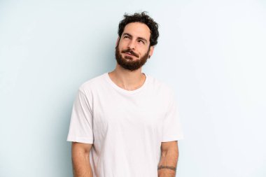 Genç, sakallı bir adam kafası karışmış ve kafası karışmış görünüyor. Bir sorunu çözmeye çalışıyor ya da düşünüyor.