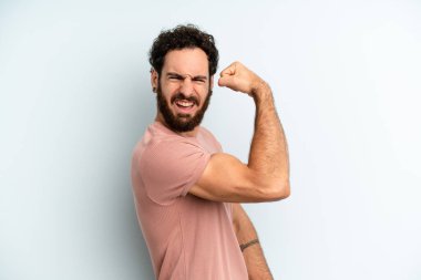 Genç, sakallı, mutlu, tatmin olmuş ve güçlü, kaslı kaslı, kaslı, spor salonundan sonra güçlü görünen bir adam.