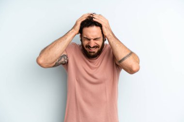 Genç, sakallı bir adam stresli ve hayal kırıklığına uğramış hissediyor. Yumruk yumruğa, yorgun, mutsuz ve migren ağrısı çekiyor.