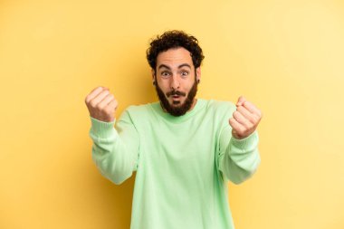 Genç, sakallı bir adam inanılmaz bir başarıyı kutluyor. Kazanan gibi görünüyor. Heyecanlı ve mutlu görünüyor.!